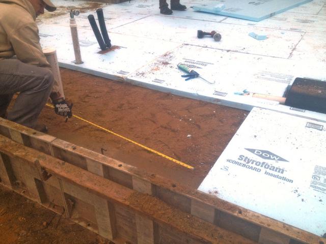 Rigid foam insulation will extend under the full slab and over the top of the footing wall to completely isolate the slab from the ground and the footings.