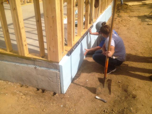 After pouring the slab, 2 inches of rigid foam is installed along the exterior of the wall from the bottom of the footing up to the roof eaves. The under-slab insulation, also visible in this picture, isolates the slab from the ground, while the slab-edge insulation provides additional protection against freezing.
