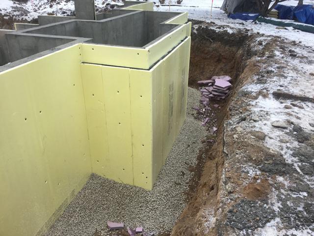 The concrete basement walls and floor are wrapped in a thermal blanket of R-10 rigid foam insulation.