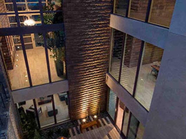 The two-story slab-on-grade construction incorporates vaulted double-height second-story ceilings and interior courtyards to flood interior spaces with natural light.