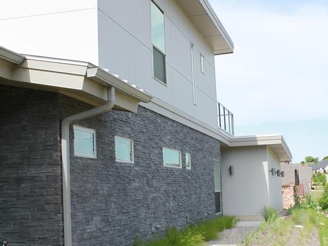 Fiber cement and stone siding provide a durable surface for the exterior walls, while overhangs protect walls and windows from high overhead summer sun.