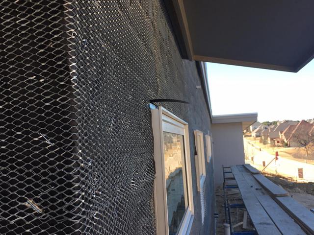 A rain screen covers the felt paper to provide a drainage gap behind the stone siding.