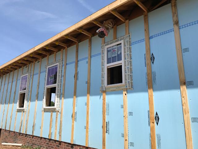 Over the taped rigid foam board, 2-by-4 furring strips were attached with structural screws to provide a ventilating air gap and drainage plane under the engineered wood lap siding.