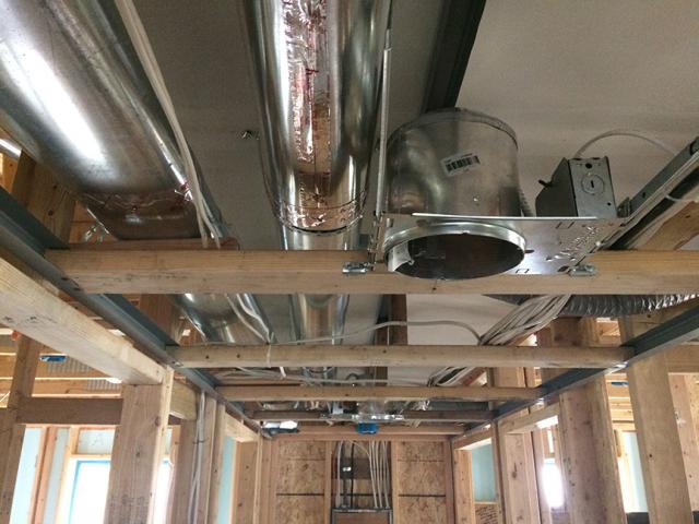 Drywall was installed as an air barrier above the central hallway duct chase prior to installing the trunk ducts.