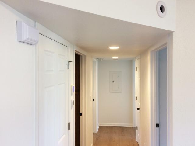 The dropped ceiling in the hallway conceals the main trunk line for the duct system, which distributes heat from the 97% AFUE gas furnace. The furnace can modulate down to 5 kBtu to match the home's low heating loads. The small round hole in the soffit is a heat register for one of the 2.5-inch-diameter supply ducts that connect to the trunk duct.