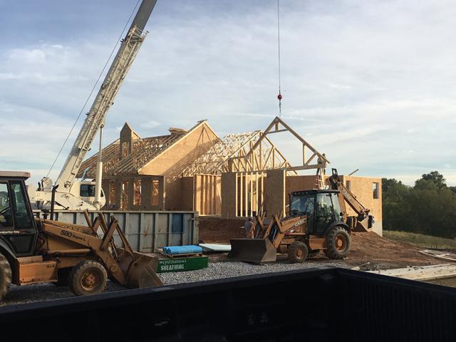 Roof trusses are set into place on the 6.5-inch, R-23 SIP walls. A 4.5-inch SIP insulates the first-floor rim bands, which are then sealed with 1 inch of closed-cell foam and an R-19 batt between the floor joists. Every crack and joint is sealed using low-expansion foam and caulk.