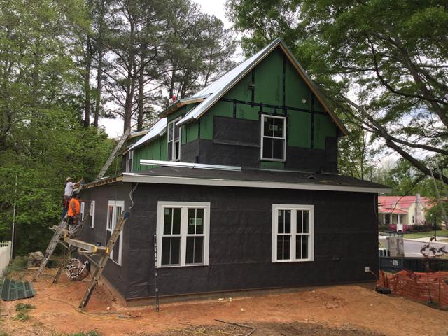 Over the coated OSB sheathing the builder installed a rain screen product that includes a corrugated plastic layer, which provides an air gap and drainage plane between the sheathing and the cladding. The rain screen product includes a mesh fabric layer that is folded over the bottom edge to form an insect screen.