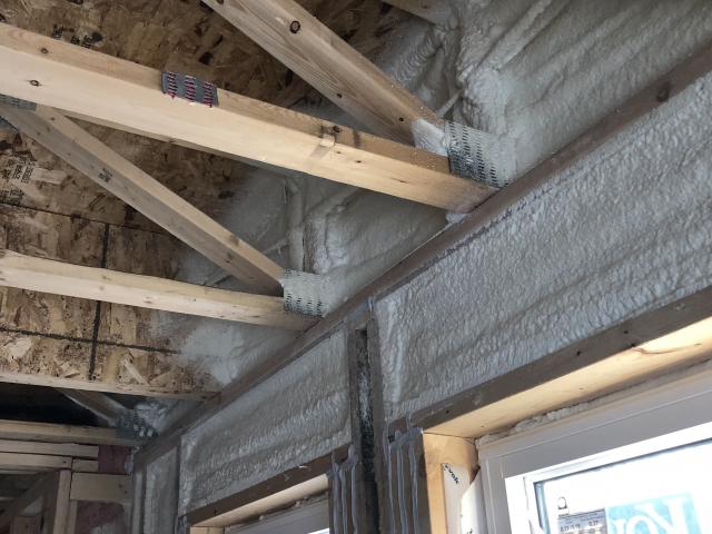 Spray foam insulation fills the headers above the windows and also insulates and air-seals the rim joists, while caulking was liberally applied to seal all wood to wood joints in the framing.