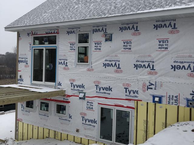 Taped house wrap provides a weather-resistant barrier over the rigid foam, which wraps the above-grade walls as well as the below-grade walls, which are first covered with a polymer-enhanced asphalt liquid-applied waterproof membrane.