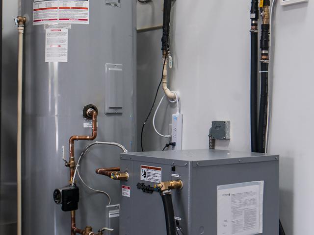 The ground source heat pump is equipped with a 120-gallon storage tank and a tankless gas water heater that serves as a booster heater.