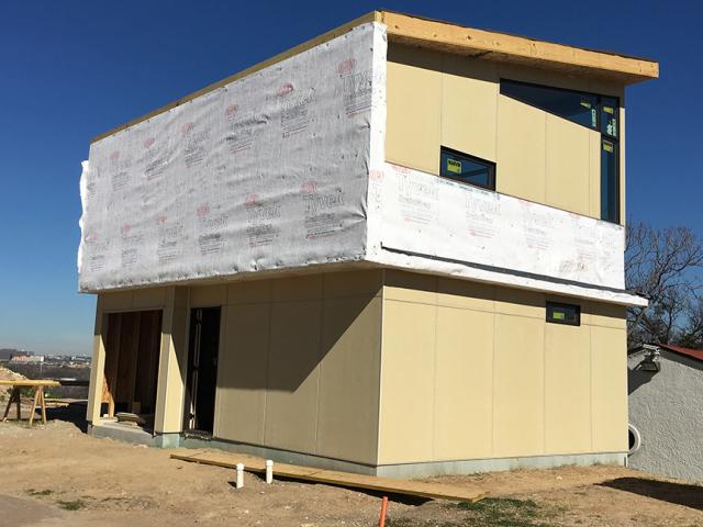 Fiber cement panels cover the compact two-story slab-on-grade structure.