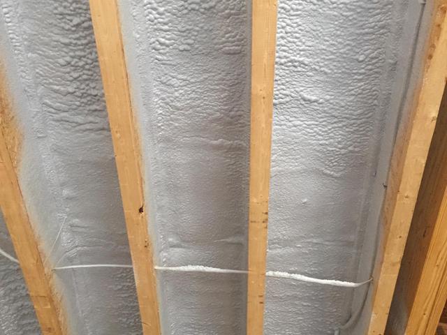 Spray foam insulation air-seals and insulates the floor above the garage.
