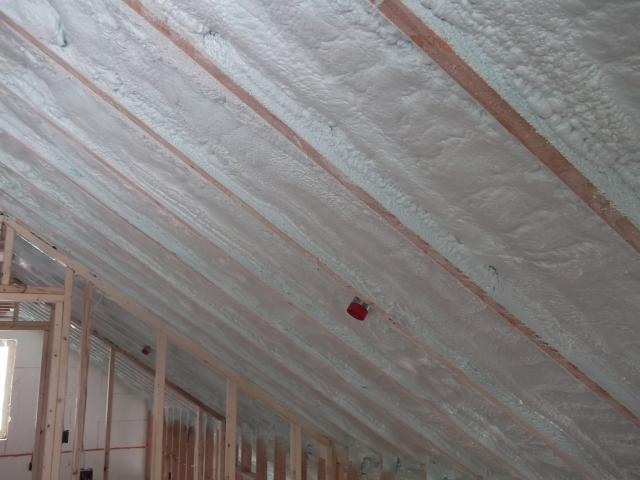 A continuous attic thermal blanket at the underside of the roof deck consists of 11 inches of open-cell spray foam plus 2.75 inches of closed-cell spray foam that completely air seals the attic, provides an R-69 insulation value, and minimizes the risk of ice dams.