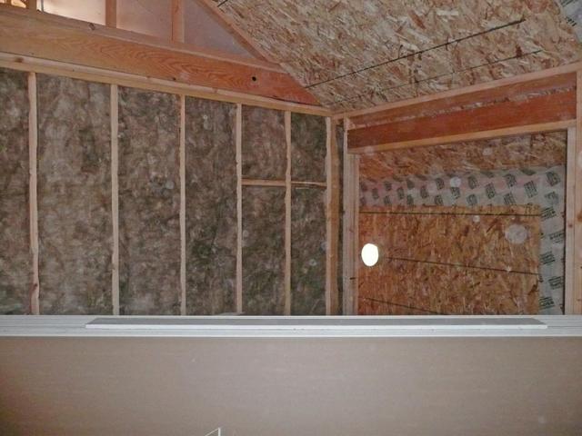 The wall to the right shows tape covering the seam where two structural insulated panels (SIPs) join. SIPs sandwich a block of foam insulation between two panels of oriented strand board. Taping the seam helps to block air leaks and provides draft protection.