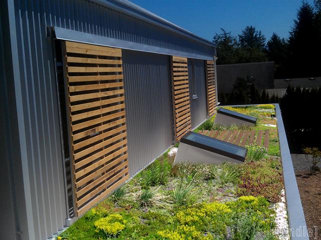 Sliding wooden screens provide shading on south-facing windows, while the planted â€œgreenâ€ roof helps control storm water runoff.