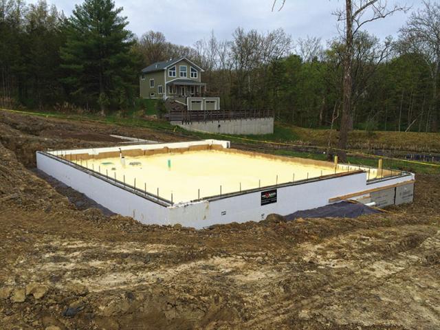 Closed-cell spray-foam insulation forms a continuous thermal blanket beneath the foundation slab.