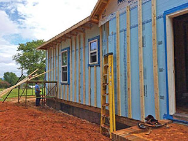 Rigid foam insulation with taped seams serves as a continuous thermal blanket, comprehensive draft protection, and continuous wall water barrier over the OSB sheathing. Furring strips provide an air gap and drainage plane between the OSB and the engineered wood siding.