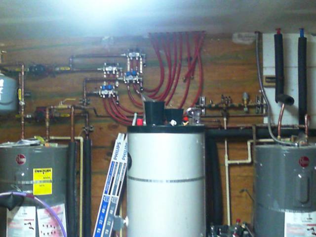 An ultra-efficient air-to-water heat pump provides radiant floor heating and domestic hot water for the home. The system includes a 50-gallon storage tank for the hot water.