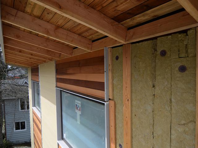 The 2-by-6 wall assembly is covered with coated OSB sheathing taped at the seams, 3 inches rigid mineral wool insulation, and 1/4-inch rain-screen battens, while 5.5 inches of fiberglass batts fills the walls.