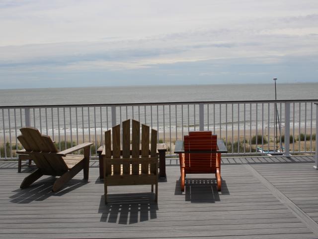 Full-width decks on the ocean-facing side of the home provide commanding views while the gabled roof behind has unobstructed sunlight for the 13.1-kW PV array. Eight-foot setbacks on this 50-foot-wide beachfront infill lot left only 34 feet of buildable width so the home rises 32 feet up from its 35-foot deep piling and grade-beam foundation.