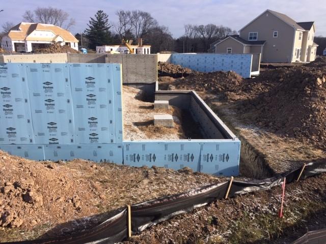 The basement walls of this cold-climate home are wrapped in 1-inch (R-5) of rigid XPS foam on the outside and 1-inch (R-6.3) rigid polyisocyanurate foam on the inside plus R-19 fiberglass in the finished interior walls.