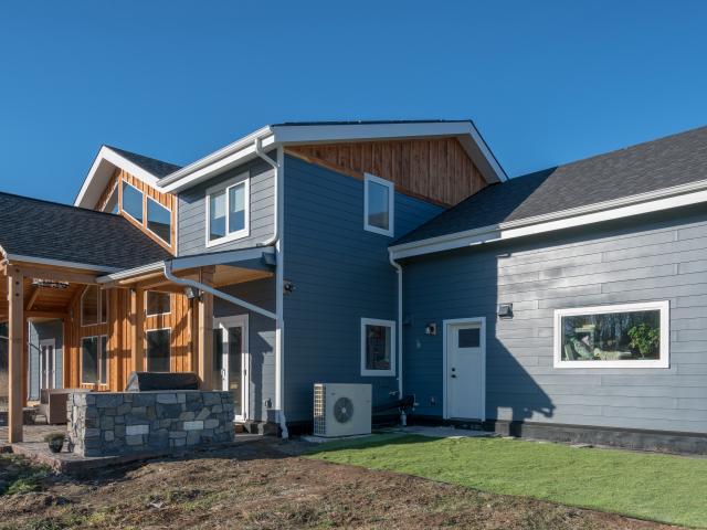 Overhangs block high summer sun but let in lower winter sun for beneficial heating. Durable fiber cement plank siding and cedar details cover the SIP home.