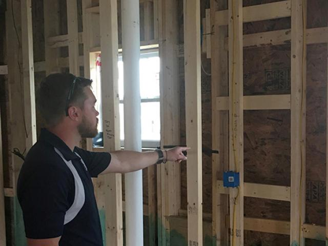 A member of the construction staff points out the advanced framing features in the home, including ladder blocking at interior-exterior wall intersections to allow more room for insulation in the 2-by-6, 24-inch on-center walls. The framing is also treated with borate for moisture and pest resistance.