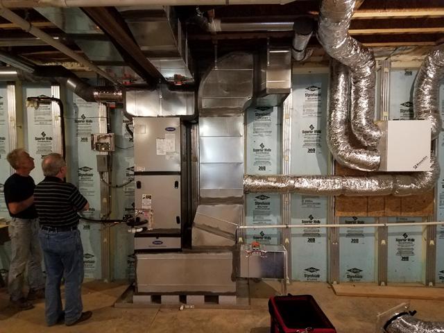 The precast insulated concrete walls of the basement provide a conditioned space for the high-efficiency (18 SEER, 9.5 HSPF) air-source heat pump, with its variable-speed fan, five-stage compressor, and MERV 11 filter.