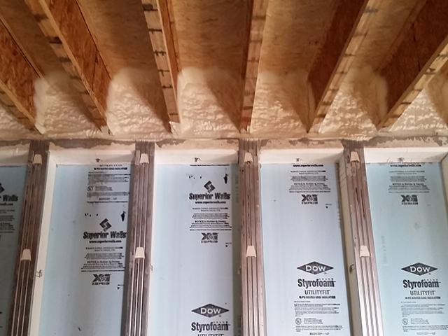 The rim band connecting the basement walls to the floor joists is spray foamed to provide air-sealing and insulation in this hard-to-seal juncture.