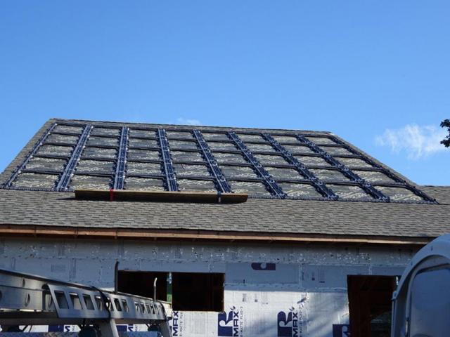 The photovoltaic panels sit in a heavy-duty plastic tray that was installed directly on the roofing underlayment. The roofing shingles are installed around but not under the tray so if they need to be replaced, the panels can stay in place.