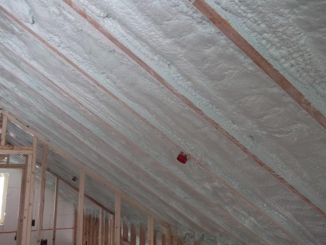 A continuous attic thermal blanket at the underside of the roof deck consists of 11 inches of open-cell spray foam plus 2.75 inches of closed-cell spray foam that completely air seals the attic, provides an R-69 insulation value, and minimizes the risk of ice dams.