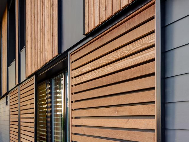 Sliding cedar panels on the south side of the home allow the homeowners to manage solar heat gain in the natural comfort home.