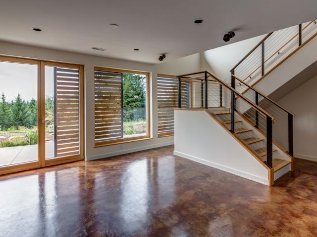 The home's stained concrete floors provide natural comfort balancing by absorbing heat during the day to avoid excessively high temperatures and releasing it at night when the rooms need heating. Heat gain is controlled using exterior cedar panels that can be slid in front of windows to block out unwanted sunlight on hot summer days.