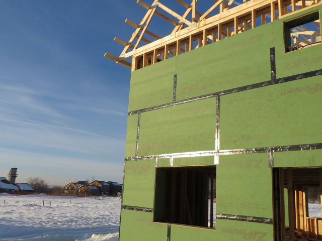 An oriented strand board (OSB) wall sheathing with integrated water barrier and taped seams provides a whole-house draft barrier.