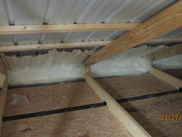 The high-efficiency attic insulation system starts with spray foam to insulate and air-seal the tops of the outer walls and to seal the bottom edge of the baffles so that ventilation air from the soffit vents is directed up along the underside of the roof where it is needed, rather than blowing through the edge of the attic insulation.