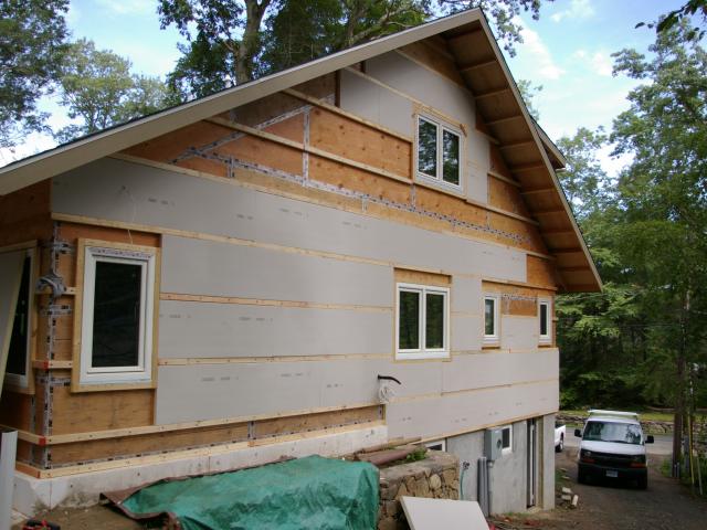 Comprehensive draft protection is achieved by sealing all of the plywood sheathing seams with tape then covering the home with two layers of rigid closed cell foam board, which forms a continuous exterior thermal blanket.