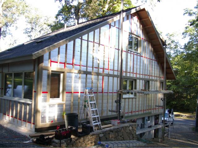 The complete dry-by-design wall system includes draining house wrap between the two layers of rigid foam board, taping the seams of the second foil-faced layer to form a water barrier, and installing furring strips to provide an air gap between the insulation and the siding.