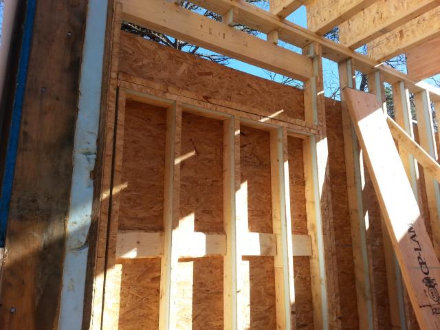 The high-efficiency wall framing shown here uses 2-by-4 studs with a 1.5-inch layer of rigid foam glued to one edge to block heat loss and gain through the wood.