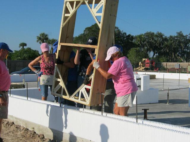 Volunteers set a window frame in place in the insulated concrete walls. All of the windows are high-efficiency double-pane windows with an invisible low-emissivity coating that keeps solar heat out in the summer and heat inside in the winter. The insulated vinyl frames and argon gas filling  also reduce heat transfer through the panes.